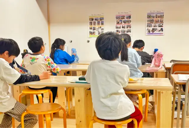 放課後の時間に、子どもたちが机を囲んで活動や学習に取り組んでいる様子